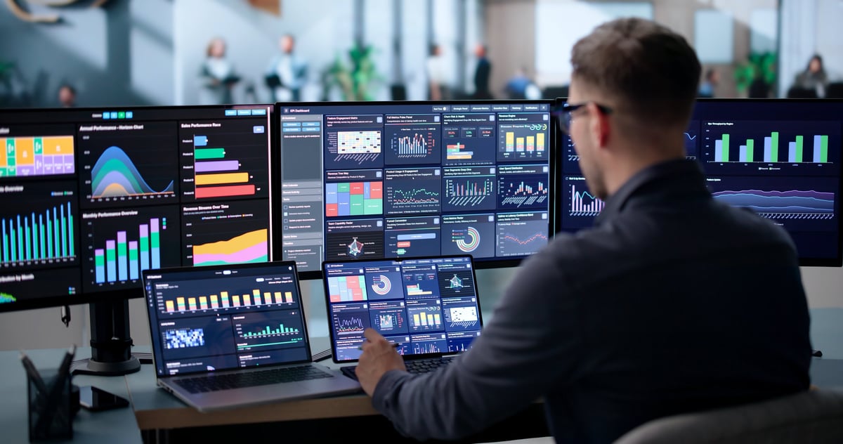 Young Data Analyst Reviews Financial Dashboard On Laptop In Office